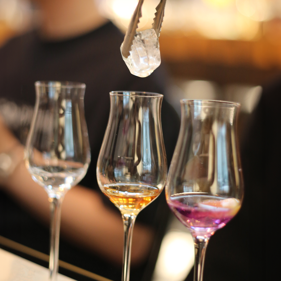 Close-up of Brass Lion gin samples in tasting glasses with ice cube being added during a guided tasting session.
