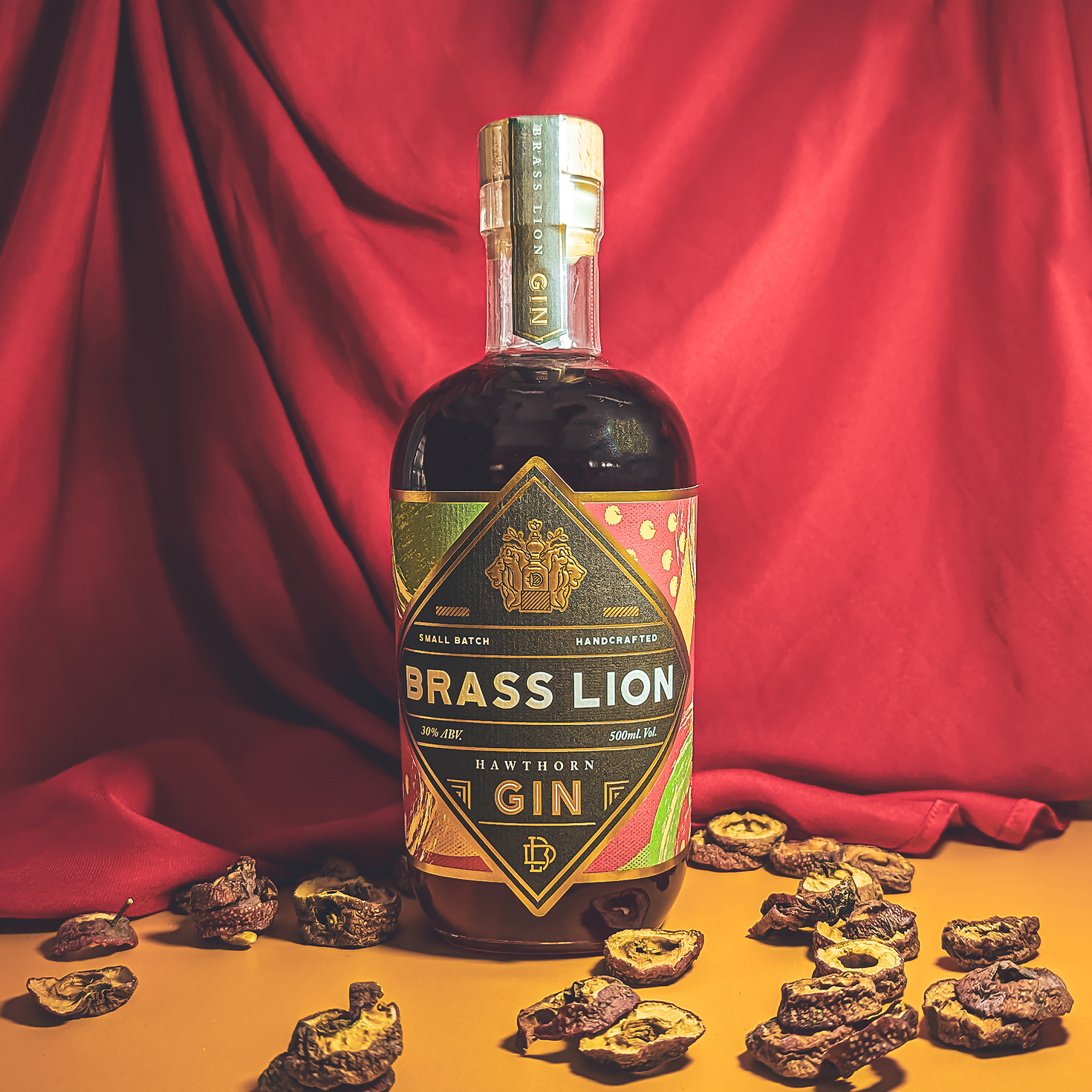 Brass Lion Hawthorn Gin bottle with dried hawthorn slices on a festive red background