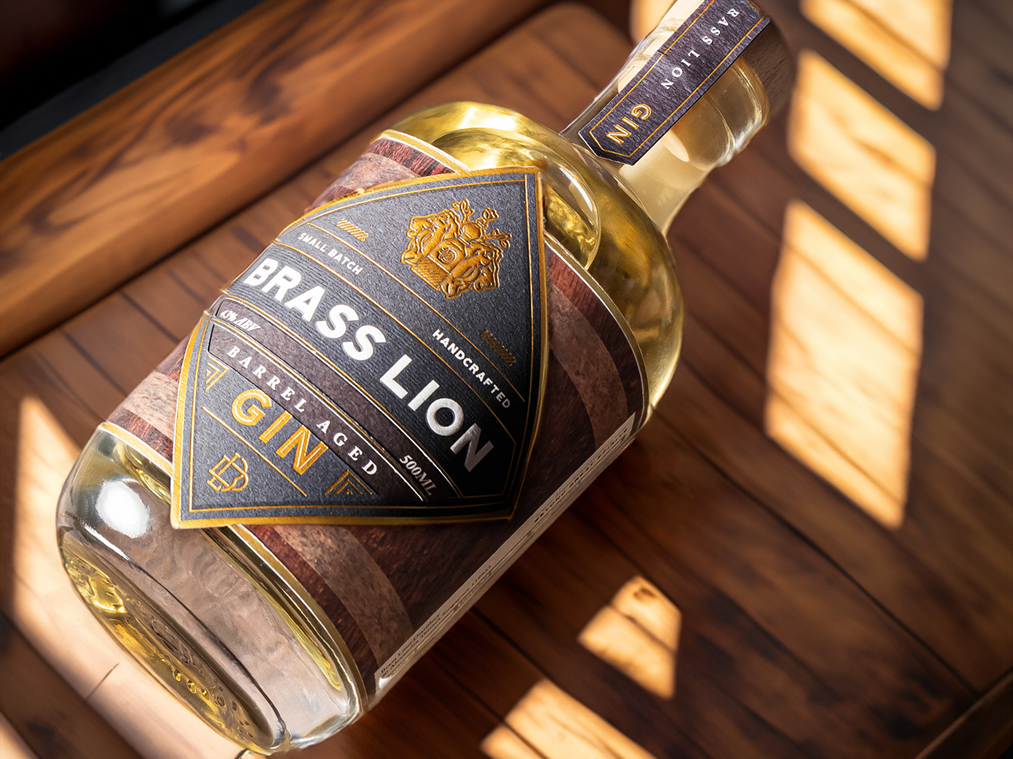 Brass Lion Barrel Aged Gin bottle lying on a wooden surface with natural sunlight